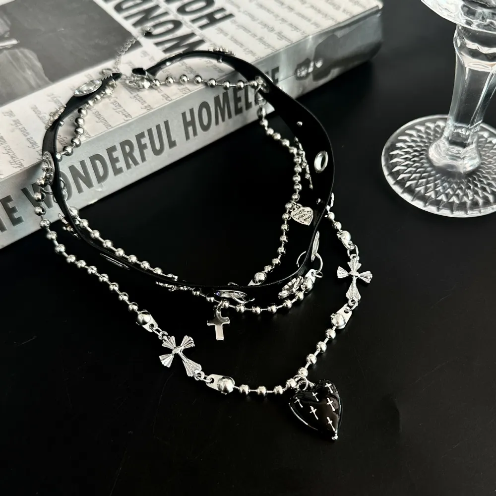 Cute? Dark? A little dangerous? 🖤  Why choose one?  This layered choker mixes edgy silver-tone chains with delicate bows, crosses and a black heart centerpiece—giving you that perfect dark feminine aesthetic.