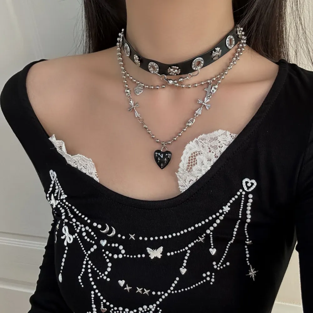 Cute? Dark? A little dangerous? 🖤  Why choose one?  This layered choker mixes edgy silver-tone chains with delicate bows, crosses and a black heart centerpiece—giving you that perfect dark feminine aesthetic.