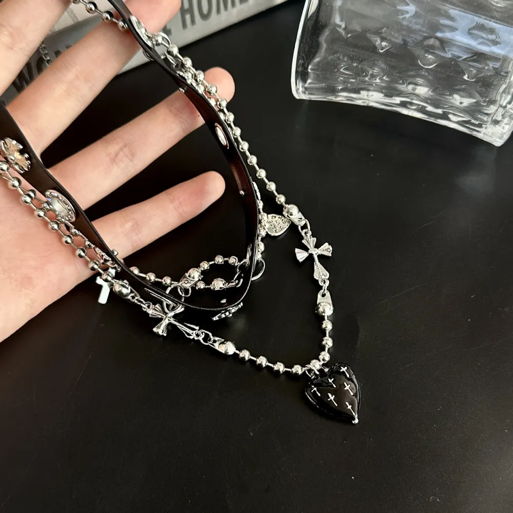 Cute? Dark? A little dangerous? 🖤  Why choose one?  This layered choker mixes edgy silver-tone chains with delicate bows, crosses and a black heart centerpiece—giving you that perfect dark feminine aesthetic.